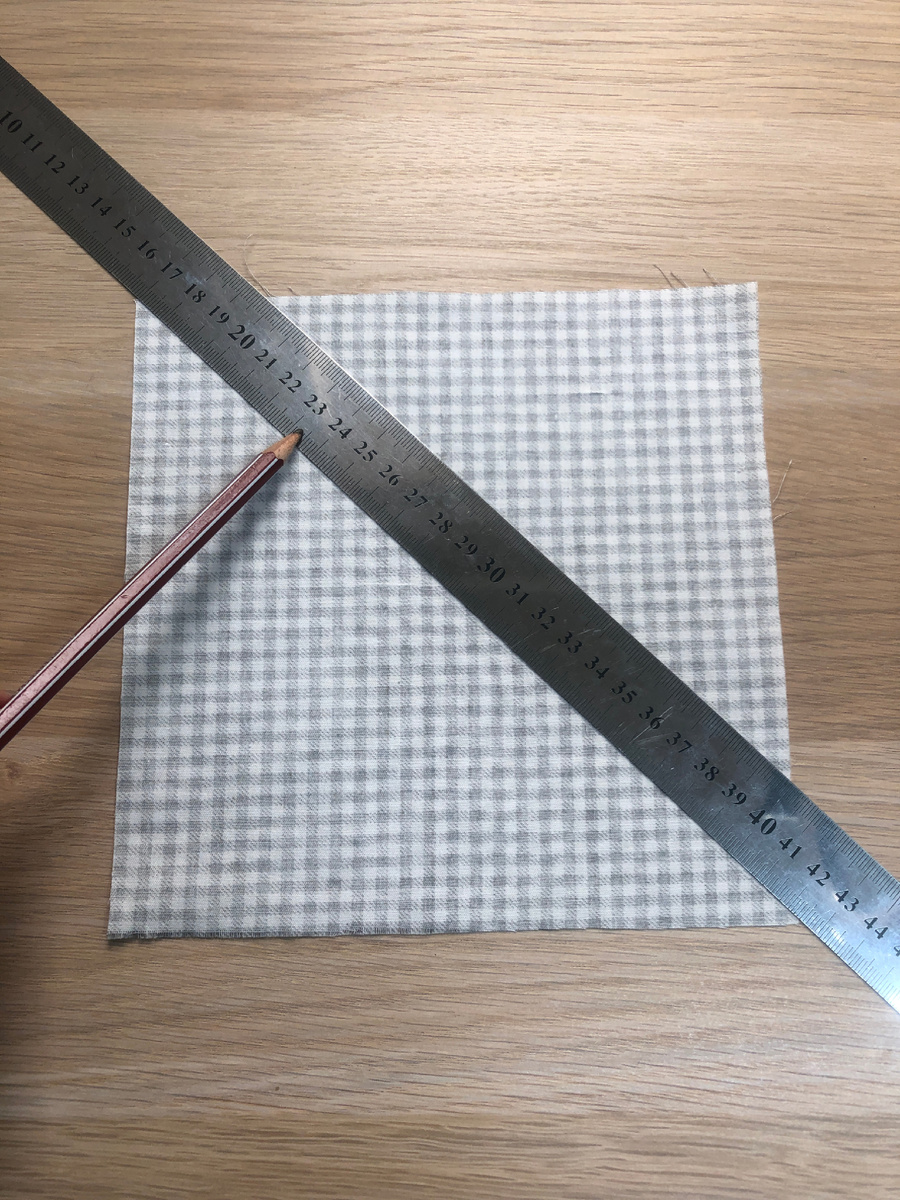 Переворачиваю ткань на изнанку, с помощью линейки, провожу линию по диагонали, от угла до угла.