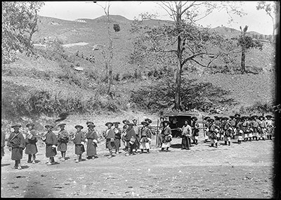 Паланкин Тринадцатого Далай-ламы, или пеп-чанг, несут в ежегодной процессии из Поталы в Норбу Лингка. Носильщики и сопровождающие окружают паланкин. На склоне холма вдалеке видны зрители