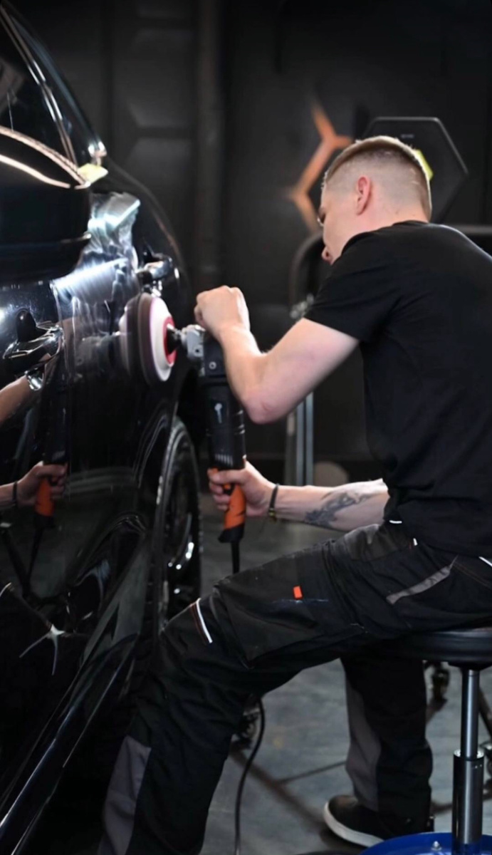 

Превью статьи блога.
Со временем лакокрасочное покрытие авто теряет былую гладкость и блеск. Чтобы восстановить его, нужно отполировать машину. Если вы хорошо обращаетесь с инструментами и автохимией, можно выполнить работу своими руками и сэкономить на посещении кузовного СТО. Рассказываем, из каких этапов состоит процедура.

Что такое полировка кузова и зачем она нужна?
Любой автомобиль используется в сложных условиях. Ультрафиолетовое излучение, сильные перепады температуры, абразивная дорожная пыль, пары топлива, легкие удары, падающие листья и следы животных постепенно разрушают краску. Со временем в ней появляются трещины и сколы.

Полируя машину абразивными инструментами, вы снимаете поврежденный слой лакокрасочного покрытия. Кузов становится более гладким, исчезают мелкие дефекты, восстанавливается блеск нового авто. Чтобы сохранить такой эффект надолго, машину покрывают специальными защитными средствами.

Автомобиль нужно полировать не только из эстетических соображений. В трещинах скапливается дорожная грязь, которая состоит из частичек резины, масла, горючего, противогололедных реагентов и битума. Этот «химический коктейль» быстро разъедает краску до основания. Всего за 1,5–2 года мелкий скол может превратиться в ржавое пятно, а за пять лет — в сквозное отверстие.

Полировка автомобиля своими руками
Перед началом работы нужно понимать — процесс занимает много времени, требует внимательности, аккуратности и навыков работы с инструментами. Серьезная ошибка приведет к повреждению лакокрасочного покрытия и к большим расходам на его восстановление. Беритесь за полировку автомобиля только если уверены в своих силах на 100 %. Если нет — запишитесь в специализированную мастерскую с хорошими отзывами. Еще одно обязательное условие — наличие гаража. Полировать машину под открытым небом нельзя — количество грязи в трещинах только увеличится.

Какие инструменты нужны для полировки машины?
Электрическая полировальная машинка — роторная стоит дешевле (от 3 000 рублей), но эксцентриковая работает чище (от 5 500 рублей).
Полировальные насадки средней, малой и минимальной жесткости — зеленого, желтого и белого цветов соответственно. Если у вас нет опыта работы, не покупайте меховые круги — ими легко повредить лакокрасочное покрытие. Стоимость комплекта — около 1 500–2 500 рублей.
Полировальные пасты грубой, средней и мелкой консистенции под разные круги. Лучше всего пользоваться средствами производства Rupes или Koch. Для полировки кузова своими руками хватит флаконов объемом 250 мл. Стоимость набора — около 2 000 рублей.
Маскировочная лента. Малярный скотч не подходит — он легко отрывается машинкой, но плохо удаляется руками после окончания работы. Цена рулона — до 500 рублей. Для внедорожников, микроавтобусов и больших легковушек нужны два рулона.
Мощные источники света — для ламп накаливания 100–200 Вт, для светодиодов 15–30 Вт. Желательно поставить две лампы, которые будут светить на кузов с разных сторон. Так вы лучше увидите царапины, сколы и другие неровности.
Уайт-спирит или другой обезжириватель. Стоимость — от 100 рублей за бутылку.
Полировочная глина. Цена — от 200 рублей за пакет для одной полировки автомобиля.
Жидкое мыло — желательно детское, с минимальным количеством отдушек. Стоимость — от 50 рублей за флакон.
Коврик из плотного вспененного материала. Цена — от 100 рублей.
Первый этап — очистка
Чтобы отполировать машину в домашних условиях, сначала нужно вымыть ее. Прокатитесь на мойку и сбейте грязь аппаратом высокого давления. Вернувшись в гараж, еще раз вымойте кузов автомобиля мягкой губкой. Вытрите его тряпочкой из искусственной замши, а потом микрофиброй, чтобы собрать мельчайшие капельки.

Вставьте курковый распылитель («Росинку») в бутылку с уайт-спиритом. Опрыскайте весь кузов машины и оставьте на пять минут. Еще раз вымойте автомобиль губкой. Растворите жидкое мыло в воде в пропорции 1:4 и достаньте глину для полировки из пакета. Принцип работы такой — намыливаете одну кузовную деталь, прикладываете глину и натираете поверхность круговыми движениями. Переходите к следующей части. Если вы уже можете нащупать мусор в глине, тщательно разомните кусок, чтобы грязь оказалась внутри.

Смойте оставшееся мыло и вытрите автомобиль насухо. Если у вас есть компрессор или пылесос с функцией обратного выдува, продуйте все щели и стыки. Брызните уайт-спиритом на тряпочку из безворсовой ткани, вытрите весь кузов машины, подождите, пока химия испарится.

Второй этап — подготовка
При полировке автомобиля пасты могут прилипать к любым выступающим частям. Поэтому вам нужно заклеить маскировочной лентой:

любые детали из неокрашенного пластика;
любые хромированные части;
пластиковые молдинги, шильдики и прочий декор;
резиновые уплотнители;
форсунки омывателей;
решетку радиатора;
зеркала заднего вида;
замочные скважины;
камеры и датчики;
дверные ручки;
выступающие подкрылки;
наклейки.
Чтобы отполировать автомобиль быстрее, заранее соберите все средства и инструменты. Если в гараже есть стеллаж, поставьте их на среднюю полку — на уровне плеч. Если нет, подойдет и тумбочка — на полу эти предметы будут мешать.

Закройте гараж — в него не должны попадать пыль и грязь снаружи. Поставьте лампы с двух сторон, направив лучи под углом 10–15° к кузову машины. Лучи должны скользить вдоль автомобиля, а не отражаться «в лоб». Полировка — долгая процедура, которая может занять весь день. Лучше заранее подготовить музыку или аудиокниги, чтобы не скучать.

Третий этап — полировка
Установите самый грубый полировочный диск. Нанесите на него 6 капель пасты размером с ноготь. Приложите к кузову, но не включайте. Поводите вправо-влево, вверх-вниз на участке 50х50 см, чтобы размазать средство. Не отрывая диск от кузова, запускайте инструмент. Выбирайте скорость чуть выше минимальной — от 1 000 до 1 500 оборотов в минуту.

Полируя автомобиль вручную, двигайте машинку сначала вверх-вниз, затем вправо-влево. Ведите ее медленно, без рывков. Но не задерживайте на одном месте — краска может полопаться из-за сильного нагрева. Выработав пасту, поднимите прибор и выключайте питание. Сотрите остатки средства мягкой тряпочкой.

Когда отполируете весь кузов, берите диск и пасту меньшей абразивности. Устанавливайте среднюю скорость — около 2 000–3 000 об/мин. Повторяйте процедуру. Чтобы придать кузову блеск после полировки, нужно взять самый мягкий диск и финишную пасту. Выбирайте максимальную скорость — от 4 500 до 6 000 об/мин. После окончания работы еще раз вытрите кузов уайт-спиритом, дайте ему высохнуть и снимите маскировочную ленту.

Четвертый этап — контроль качества и закрепление результата
Выведите машину на улицу и просветите мощной лампой со всех сторон. В идеале вы должны получить ровную глянцевую поверхность, как у нового авто. Если вы видите радужные полосы и разводы, нужно повторить полировку пастой со средней абразивностью и финишным средством.

Самостоятельная полировка автомобиля отнимает много времени и сил. Будет обидно, если они пойдут насмарку в первый же месяц. Поэтому машину лучше покрыть защитным средством, которое заполнит поры и не даст грязи забиваться в мелкие трещинки:

полироли на основе карнаубского воска и политетрафторэтилена стоят недорого — от 500 рублей. Но они вымываются за 3–6 месяцев;
покрытие кузова жидким стеклом обойдется в 3 000–5 000 рублей. Средство держится до года и увеличивает прочность лакокрасочного покрытия;
нанокерамические составы производятся на основе жидкого стекла и работают так же, но стоят дороже — от 10 тысяч рублей;
поклейка прозрачной «бронированной» пленки обходится в 15–25 тысяч рублей. Но взамен вы получаете защиту на 3–5 лет.
Пять правил полировки своими руками
Не полируйте соседние участки сразу. Лучше чередуйте кузовные детали, чтобы не перегреть краску.
Не полируйте ребра жесткости на изломе. Слой лака там самый тонкий, его можно стереть до основания. Двигайте диск по обе стороны, но не переходите на кромку.
Смотрите не на диск, а на участок перед ним, чтобы не зайти за края обрабатываемой детали.
Не допускайте попадания пасты в щели и стыки. Вымыть ее оттуда очень сложно.
Следите, чтобы подошва машины не соприкасалась с кузовом. При быстром вращении она может сбить краску до голого металла.
Что лучше — отполировать самому или отдать на СТО?
Если у вас уже есть опыт кузовного ремонта, вы привыкли держать в руках инструменты и знаете принцип действия автохимии, делайте работу сами и сокращайте расходы. Во всех остальных случаях лучше отдать машину в сервисный центр. Мастера позаботятся о том, чтобы полировка была быстрой и безопасной — они защитят кузов от случайных повреждений, правильно подберут средства, проверят качество исполнения работ и предоставят гарантию.