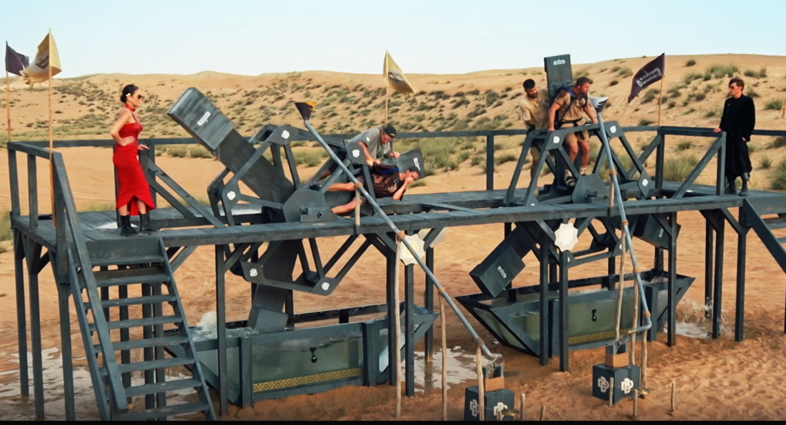 Пара Слава и Саша справилась с заданием быстрее и попала в гранд финал. Один член двойки должен был вертеть колесо, а второй (привязанный) набирать воды в рот и сплевывать ее в колбу. Из последней, когда она наполнится,  выкатывается шар и бьёт по гонгу, возвещая о победе одной из команд /https://rutube.ru 