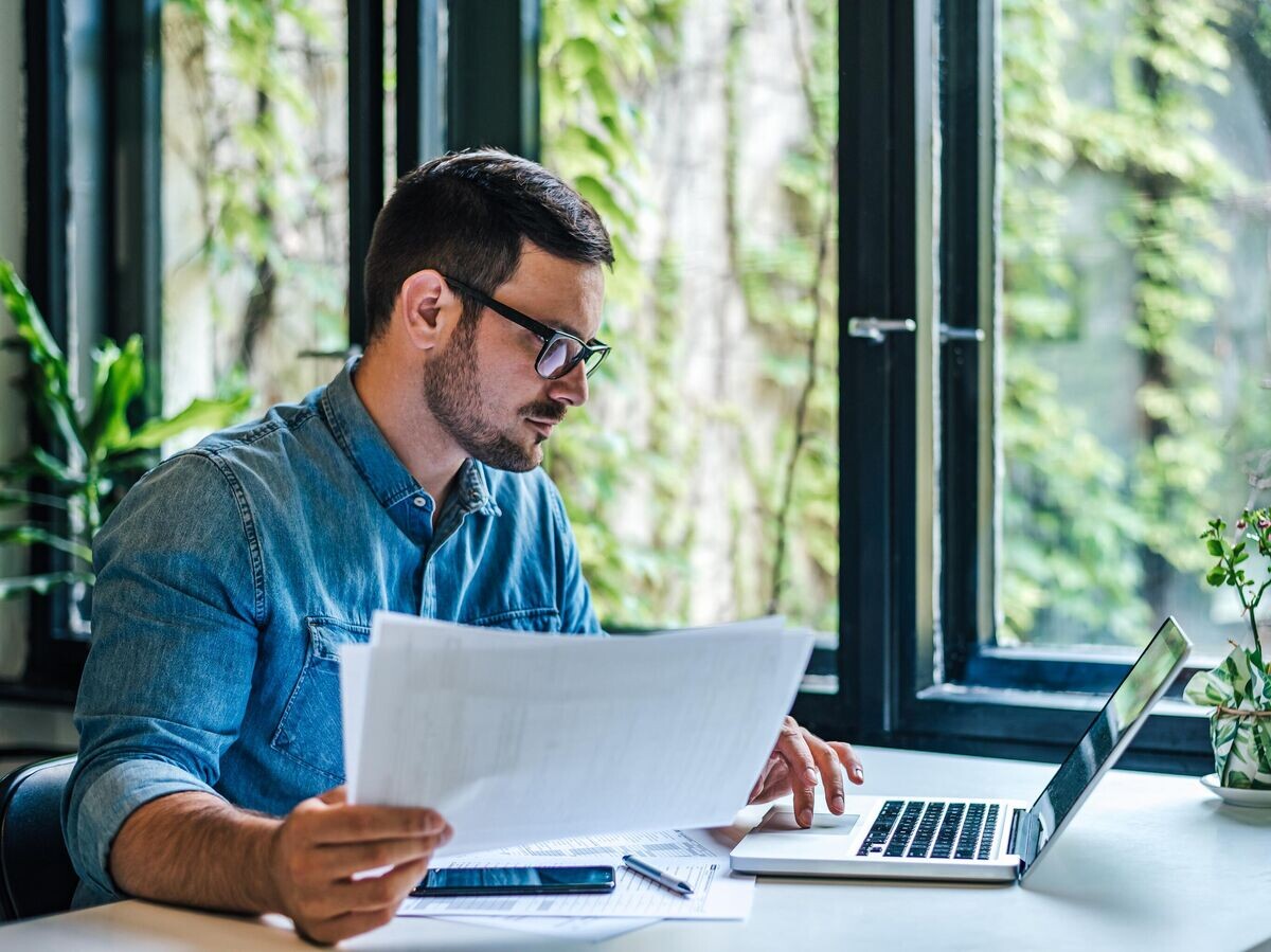    Мужчина с документами за компьютером© iStock.com / Moon Safari