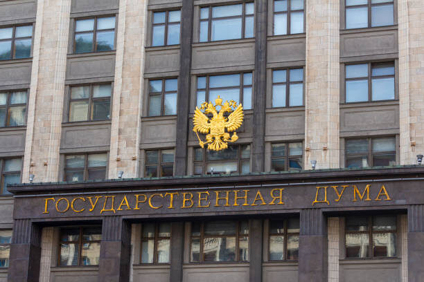    Russia, Moscow - June 21, 2020: View of russian State Duma building, also known as Gosduma. On the wall of the building hangs the coat of arms of Russia - a two-headed golden eagle.