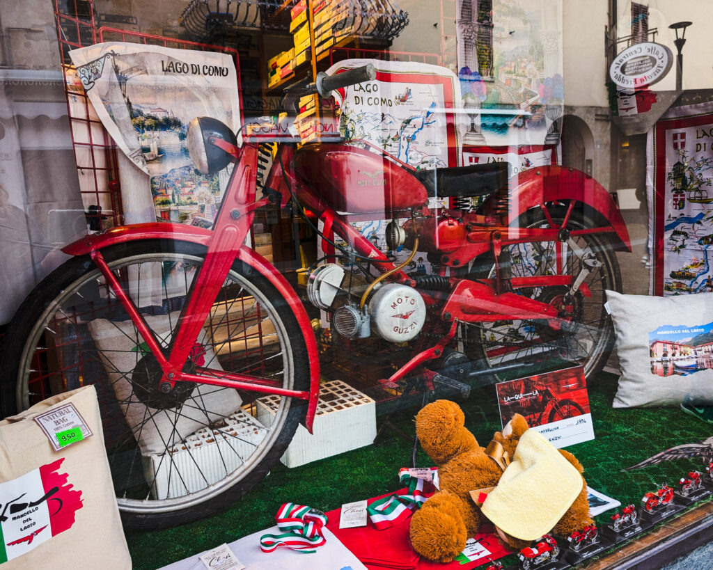 Типичная витрина магазина в Манделло-дель-Ларио во время Дня открытых дверей, с множеством безделушек Moto Guzzi и прекрасным Cardellino 1950-х годов. 