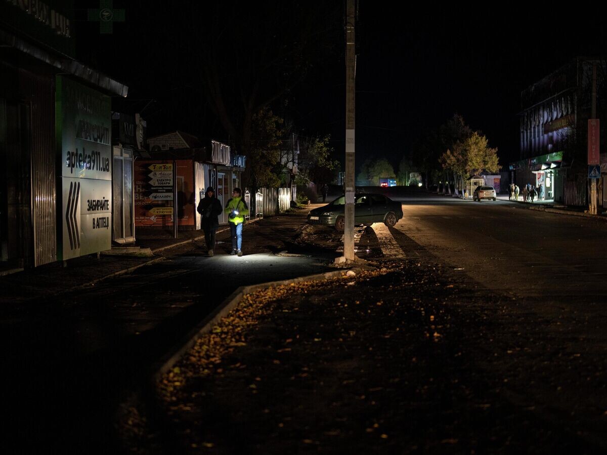    Люди идут по улице во время отключения электроэнергии в Бородянке в Киевской области© AP Photo / Emilio Morenatti