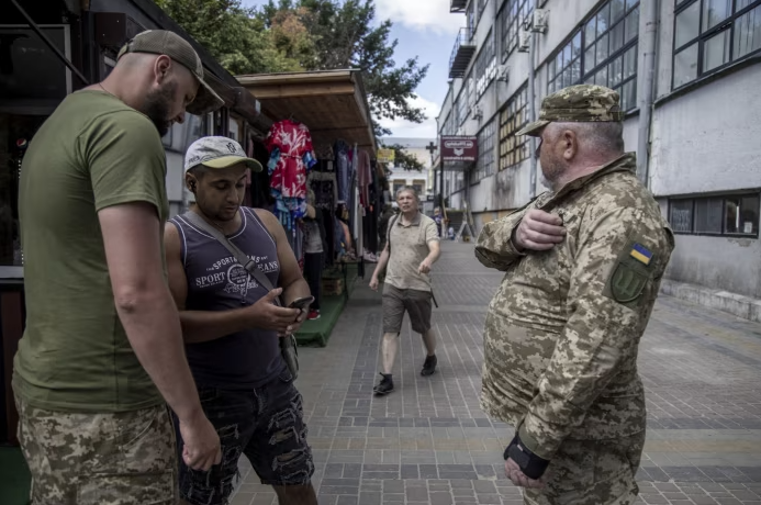 Сотрудники Харьковского областного военкомата проверяют документы гражданского лица. Миллионы украинских мужчин были вынуждены зарегистрироваться для возможной службы или столкнуться с огромными штрафами © Narciso Contreras/Anadolu/Getty Images