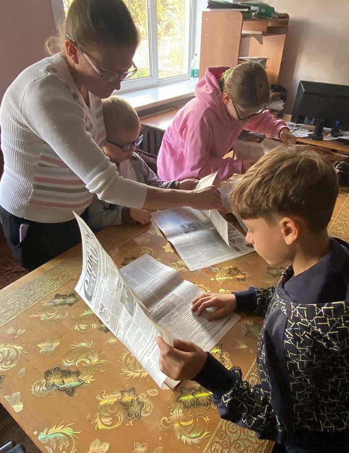 Дети листают старые выпуски газеты «Восток Алтая»