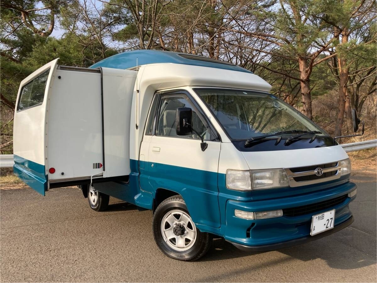 Toyota Lite Ace Camp Mate, именно "Camp Mate" можно перевести как "Друг для путешествий" или "Компаньон по палаточному лагерю"