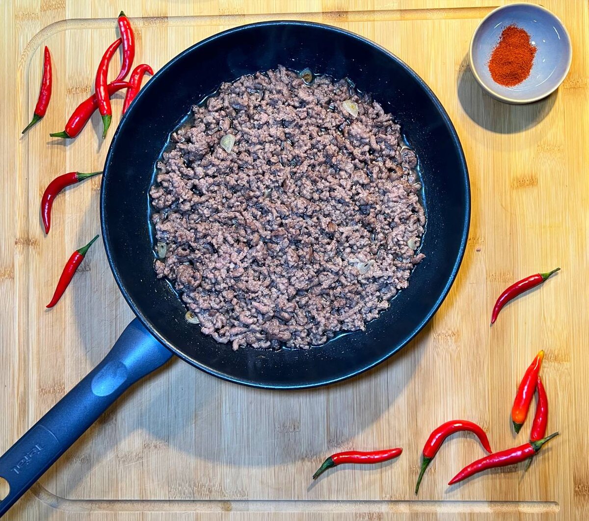 Нарежьте чеснок тонкими слайсами и вместе с фаршем отправьте в заранее разогретую сковороду.Обжаривайте фарш и чеснок на сильном огне 3-5 минут.