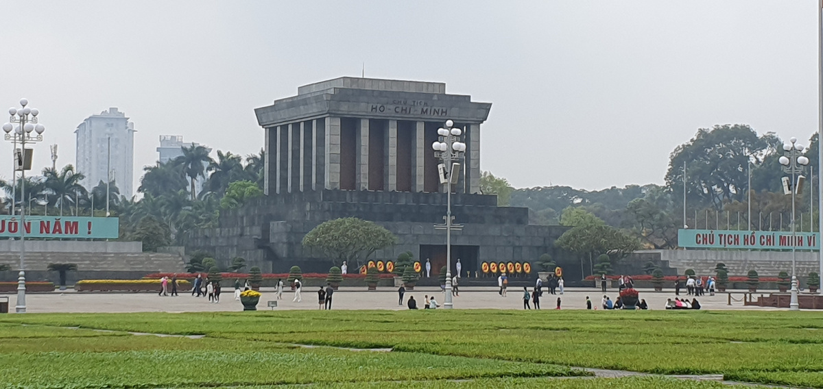 Вид на Мавзолей с площади Ба Динь. Вдоль площади перед мавзолеем посажено два ряда франжипани и 18 вечнозелёных деревьев, символизирующих вечность и бессмертие. Этот подарок преподнесён Президенту жителями равнинных провинций. Мавзолей Президента Хо Ши Мина имеет форму большого лотоса, который символизирует благородные нравственные качества вьетнамского народа и Президента.
