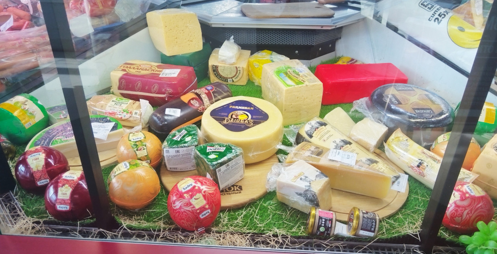 Реальный пример выкладки сыра на витрине. Какую видим ошибку? Не все сыры представлены в разрезе; целые головы сыра должны находится в глуби витрины; сыр расположен хаотично, нет логики выкладки по типам сыров. 
