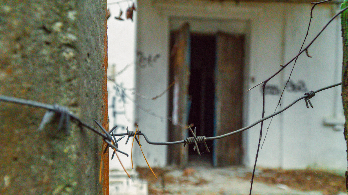 Колючая проволока, неотъемлемый атрибут многих зданий в городке