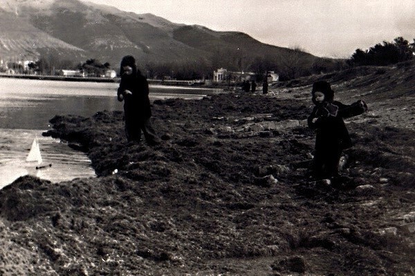    Зима. 1954 год. Территория будущего городского пляжа, покрытого морскими водорослями, выброшенными во время зимних штормов. Вдали виднеется здание партшколы (будущий кинотеатр «Чайка»). Айгуль Трофимова