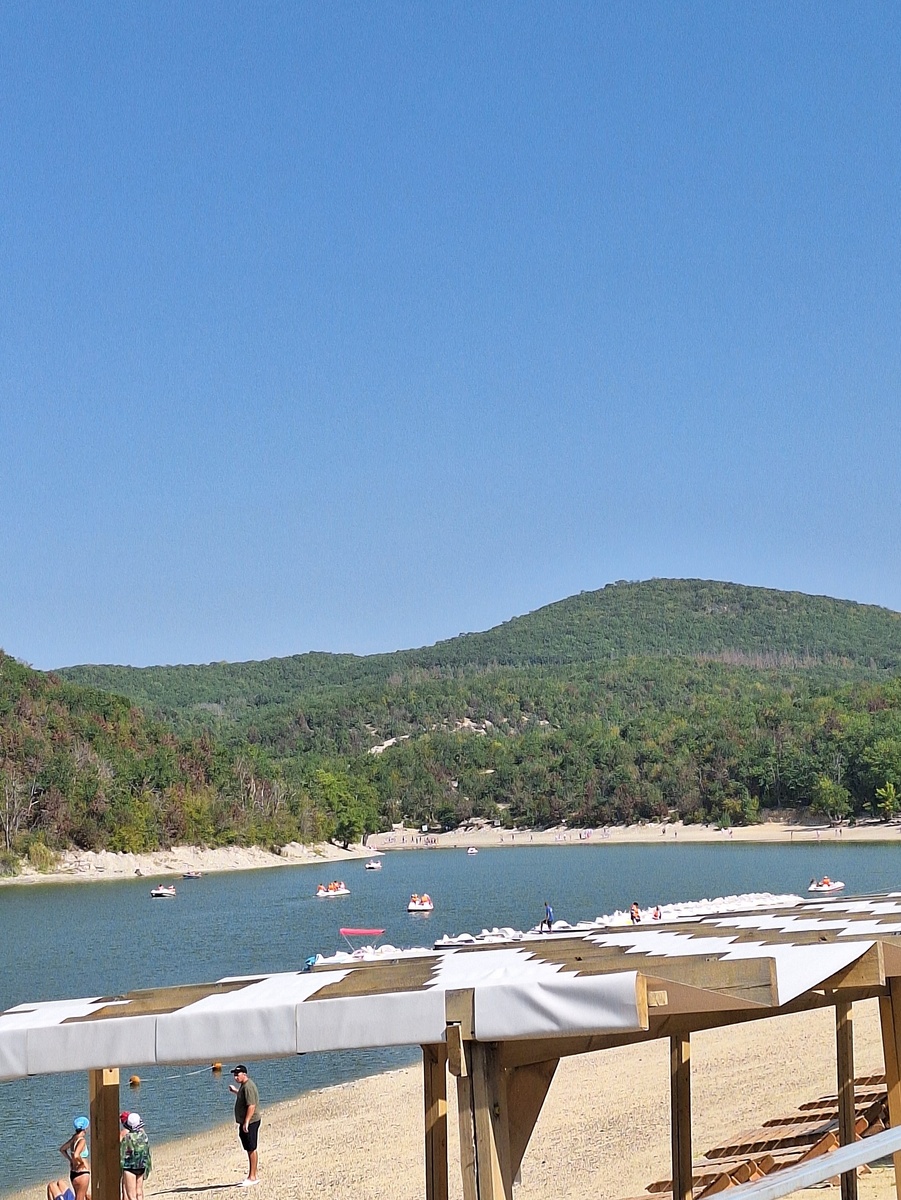 На том берегу, где озеро поворачивает, видны зелёные кипарисы, незаметные на фоне остальной зелени