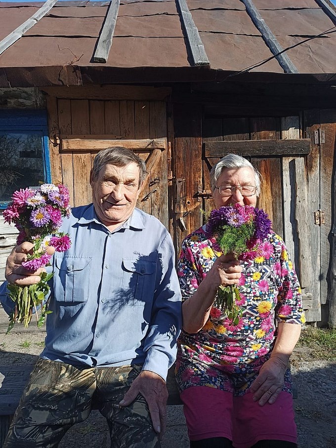 Пожилые мужчина и женщина с букетами цветов