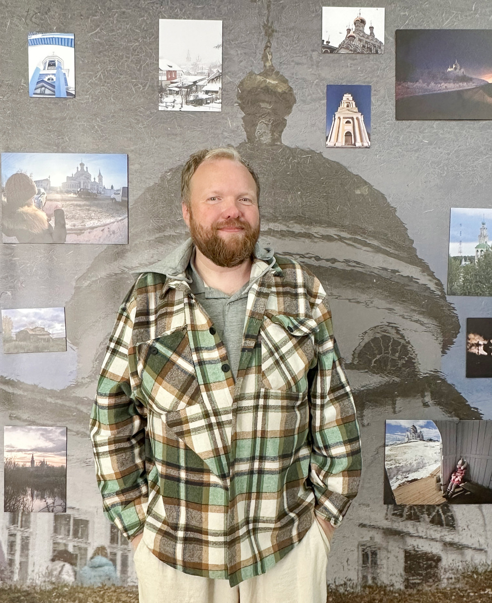 Алексей Гречищев позирует на фоне своих фотографий. Фото: Нина Трясцына