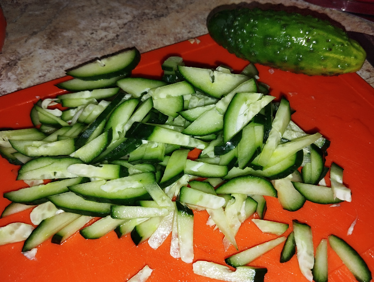 Огурец нарезан для овощного салата.