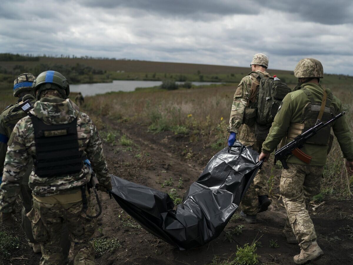    Украинские военнослужащие несут тело погибшего украинского военного в Харьковской области© AP Photo / Leo Correa