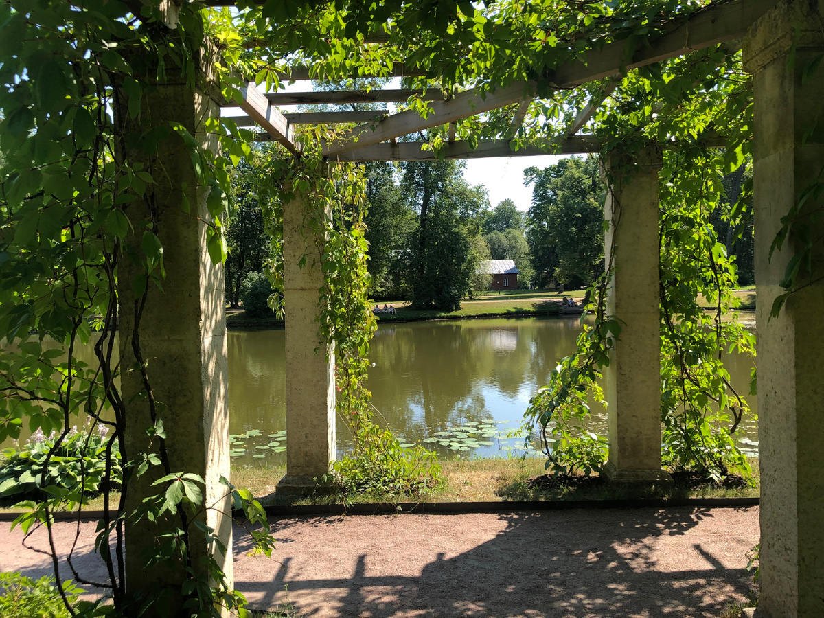 Пергола из каменных пилонов с деревянной обрешеткой рядом с видом на пруд рядом с Китайским дворцом Ораниенбаума