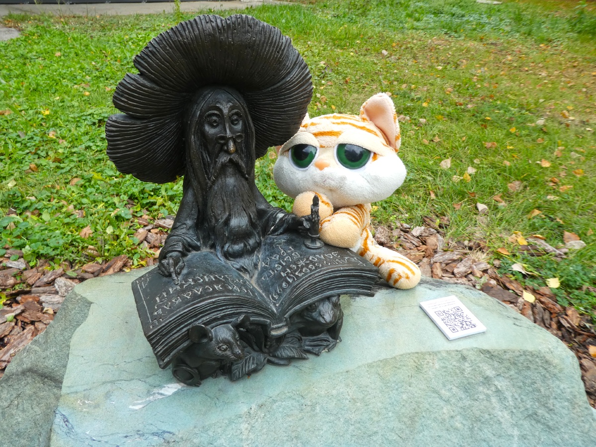 Гриб-мудрец читает книгу около библиотеки имени Сергея Есенина всего в нескольких минутах ходьбы от вокзала. Абрикос подглядывает и читает через плечо.:)