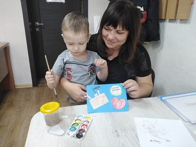 Мама помогает сыну раскрашивать открытку