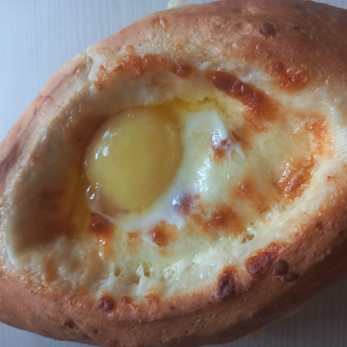 Хачапури по-аджарски — это грузинское блюдо в виде открытой лодочки с начинкой из нескольких видов сыра, сырого желтка и сливочного масла.