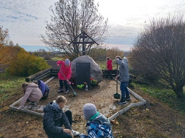 Учащиеся Москвинской школы помогают убирать памятник в деревне Ланева Гора накануне празднования региональной памятной даты – Дня памяти жителей сожжённых деревень. 2024 год.