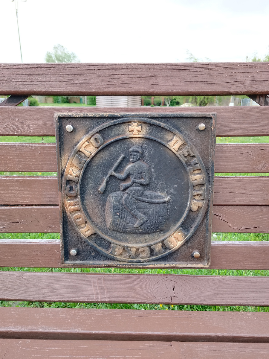 Изображение печати казаков на лавочках в Ефремовском парке в ст. Старочеркасская, современное изделие. Здесь заметны шапка, штаны, ружье, сапоги, рог и сабля. Креста и чарки не видно. Отчетливое телосложение торса мужчины без рубахи. Сидит на бочке.