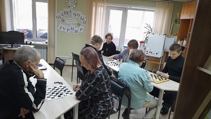 Пожилые и молодые люди играют в шашки