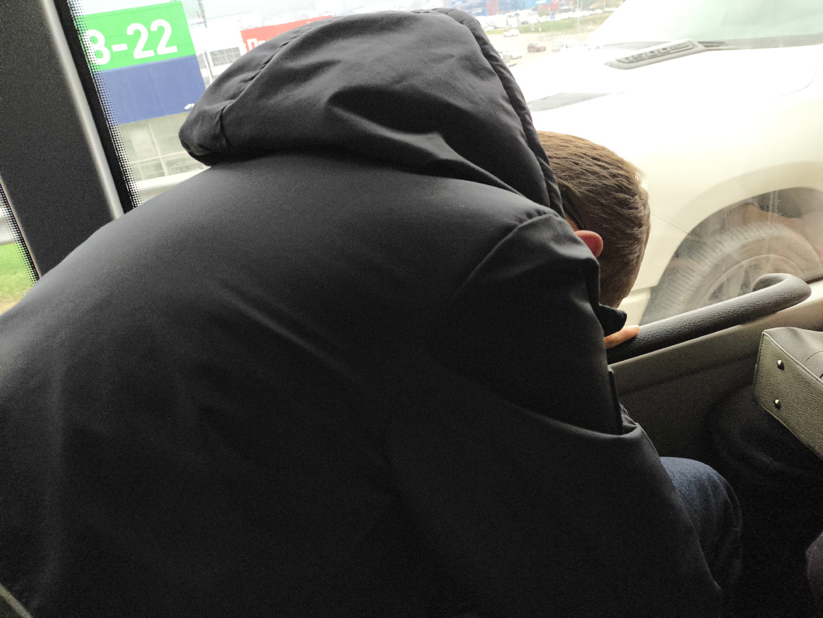 Тифлокомментарий. Гоша сидит в автобусе. Наклонился, положил голову на колени и дремлет. 