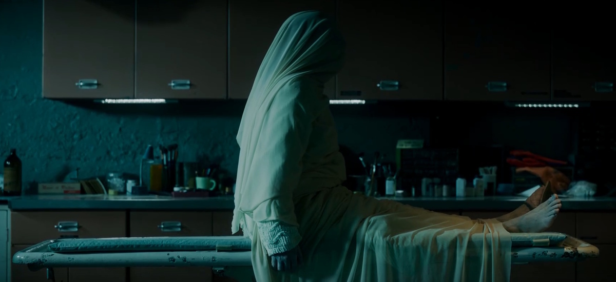 «Марджори Глик села, и простыня сползла на колени. Лицо женщины было мертвенно-бледным, с тёмными провалами глазниц»