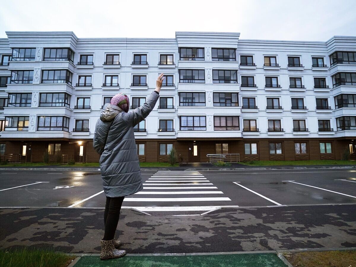   Женщина возле одного из жилых домов в Октябрьском районе Мариуполя© РИА Новости / Александр Сухов