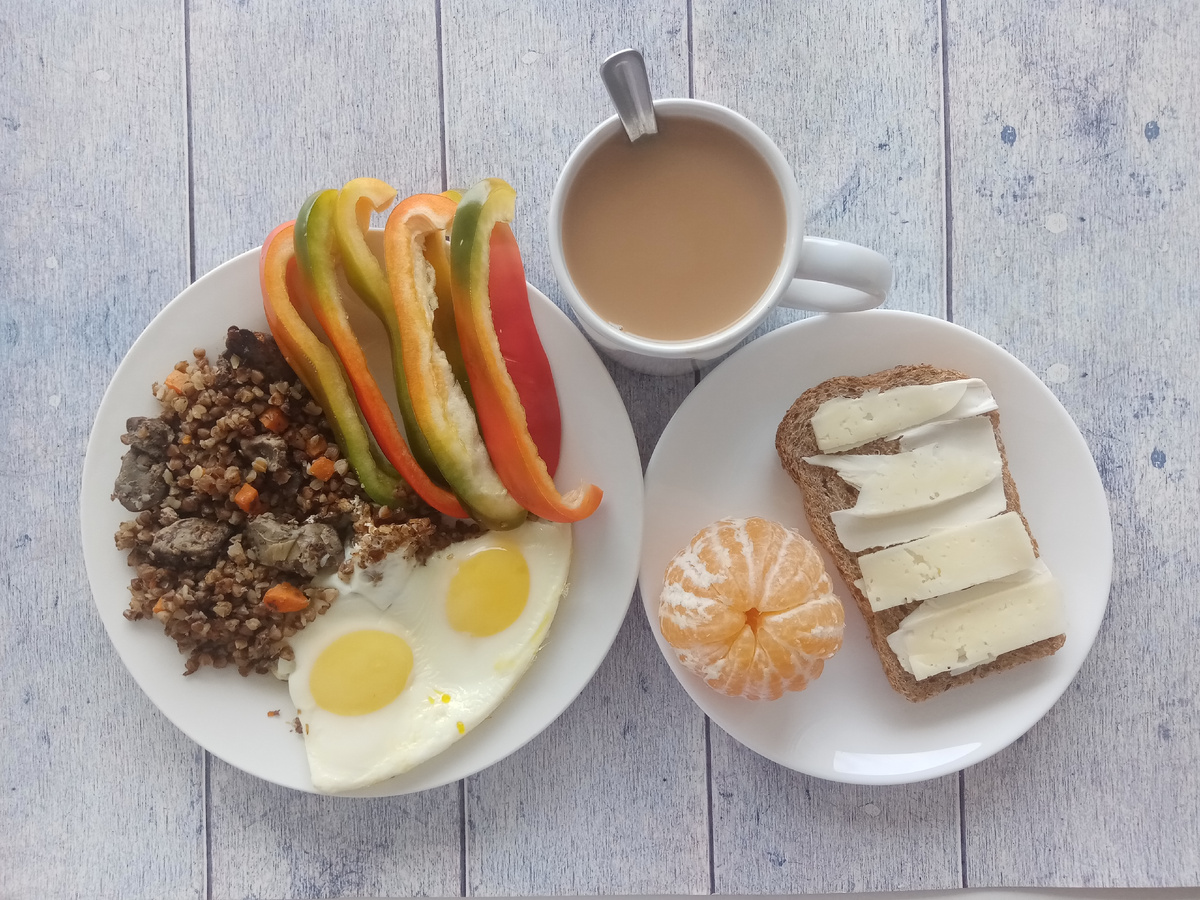 Завтрак. Яичница, гречка с печенью, перец, бутерброд с маслом и сыром, мандарин и чай с молоком и с сахаром.