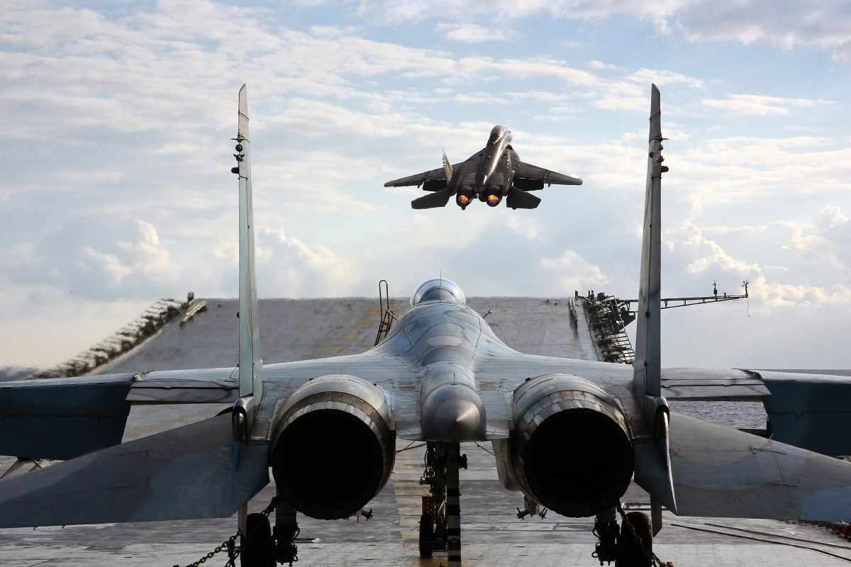 МиГ-29КУБ взлетает с ТАВКР «Адмирал Кузнецов». На переднем плане Су-33