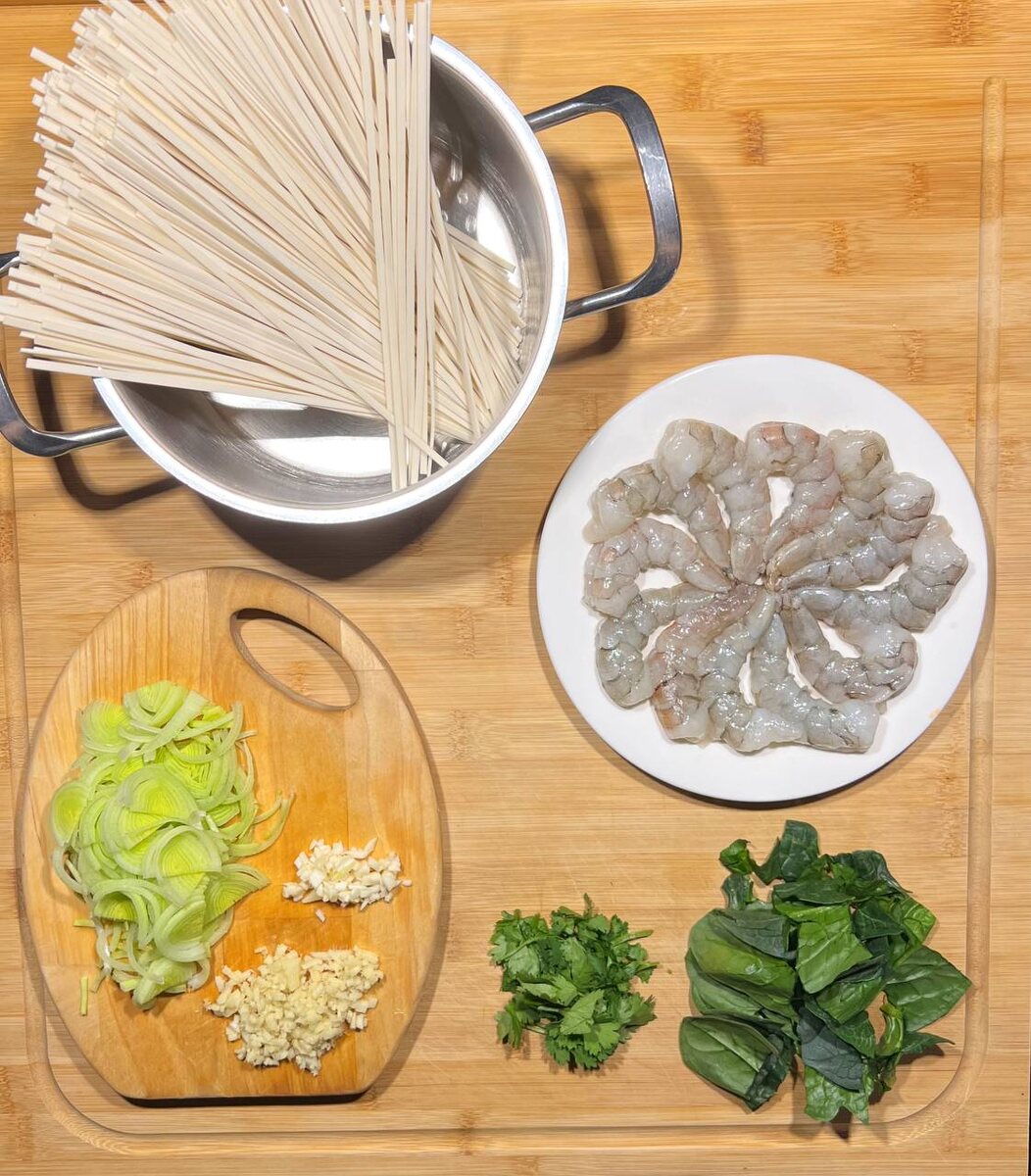 Отправьте лапшу в кипящую подсоленную воду и варите в течении 7 минут.В это время чеснок и имбирь очистите и нарубите мелко, лук нарежьте тонкими полукольцами.а зелень отделите от стеблей и нарвите руками.