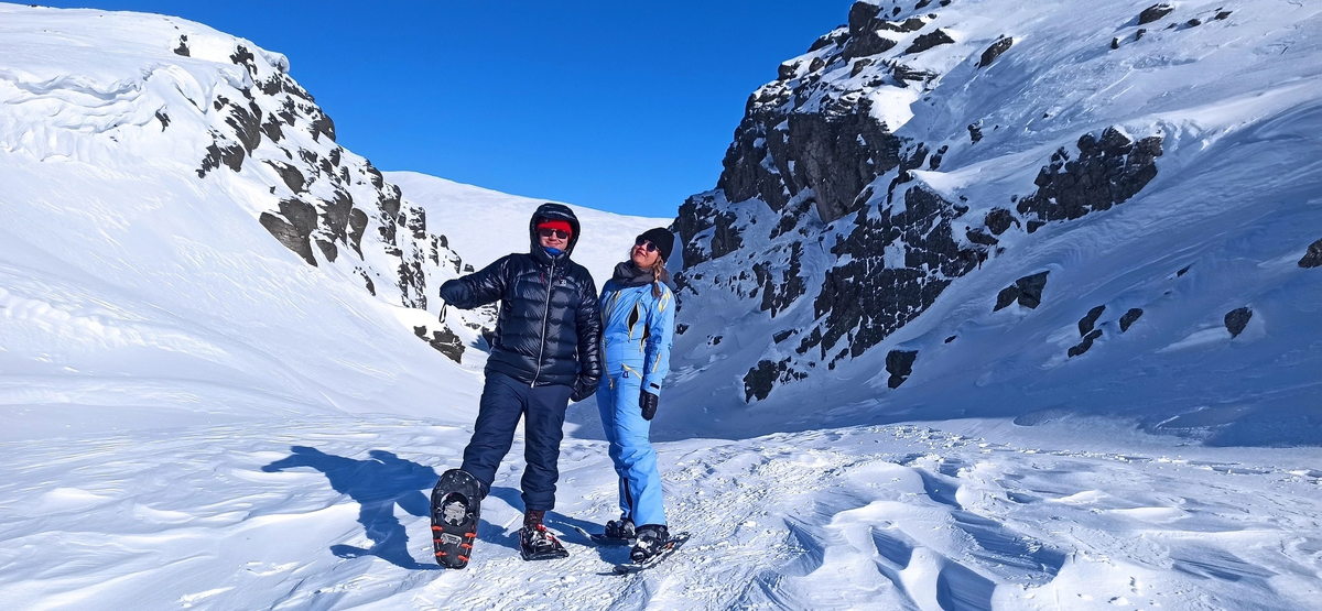 Туристы на снегоступах. На мужчине рамные снегоступы, на женщине - пластиковые. Хибины, Алявумчорр, конец марта, 2024 год