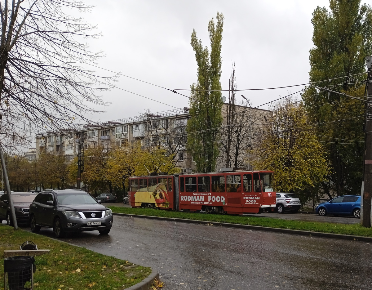 Ярко-красный трамвай на фоне обычного дома и серого неба привлекает к себе внимание!