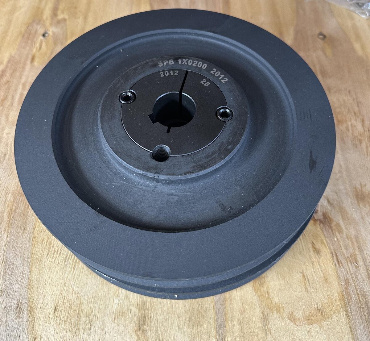 На фото представлен шкив SPB под втулку тапер буш с размером под втулку 2012 с одним ручьем 1х200. 200 мм. означает диаметр шкива, на самой втулке так же указан ее размер 2012 и диаметр вала 28 мм.                                                                                                                                                  В мире существует общепринятое обозначение для клиновых шкивов, которое основано на нескольких технических параметрах этих деталей, таких как количество ручьев, профиль ремня и диаметр по корду ремня. 
 Например, шкив с обозначением "3 SPB 500" имеет три  ручья, профиль шкива " SPB" и 500 мм. диаметр по корду ремня.