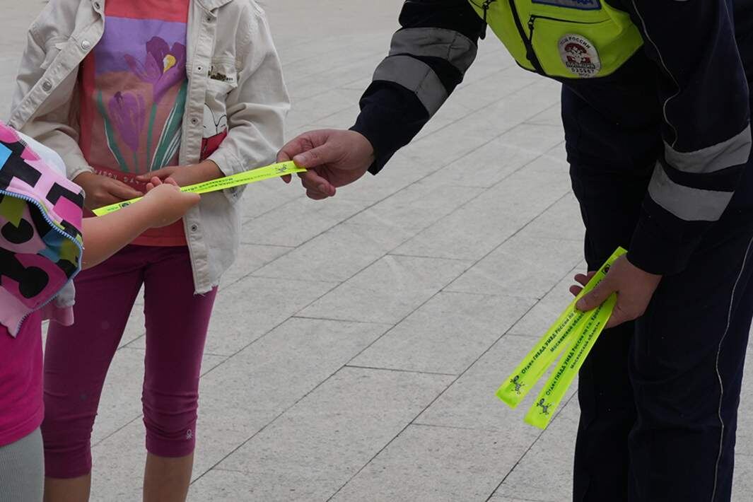 Сотрудник ГИБДД раздает детям светоотражающие элементы на одежду Фото: ИЗВЕСТИЯ/Дмитрий Коротаев