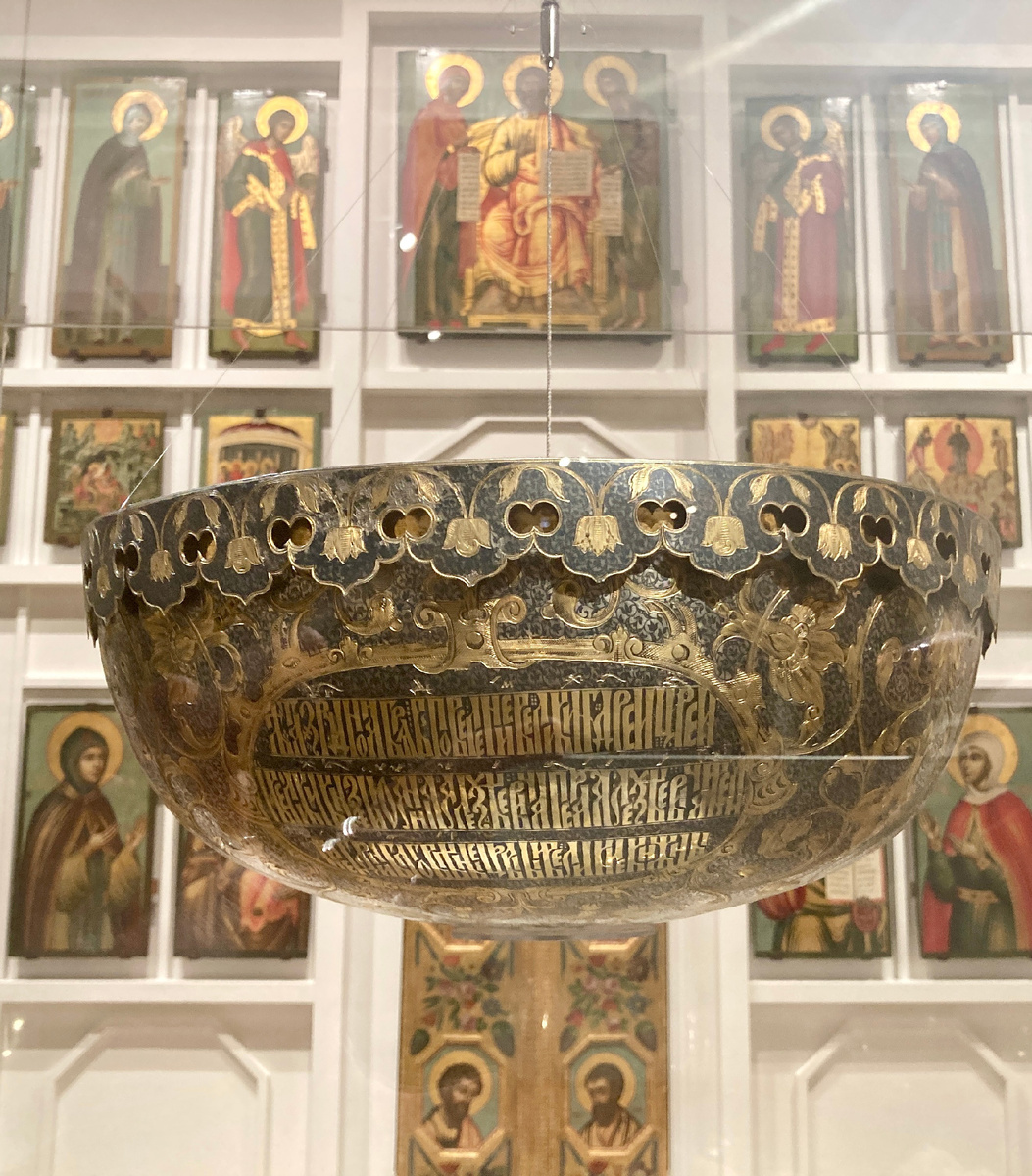 Листайте галерею.Кандило, диаметр 38 см, серебро, чернь, золочение, резьба, гравировка. В трех картушах помещены надписи: «Надпись помещена в трех картушах: «Лета 7194 (1686) июля в... повелением великих государей, царей и великих князей Иоанна Алексеевича и Петра Алексеевича и великие государыни благоверные царевны»; «и великие княжны Софии Алексеевны всея Великия и Малыя и Белыя России самодержцев построена сия лампада в Новодевичь монастырь»; «в соборную церковь Пресвятые Владычицы нашей Богородицы и Приснодевы Марии честнаго и славного ея Одигитрия чюдотворныя иконы Смоленские». Фото автора, сделано на выставке Новодевичий монастырь. Вехи истории» в Государственном Историческом музее, ноябрь 2024