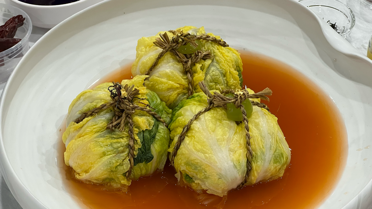 Кимчи обвязанное в клубочек с помощью веревки, а сверху украшено виноградом и золотой фольгой. Звучит и выглядит, как что-то на богатом. 