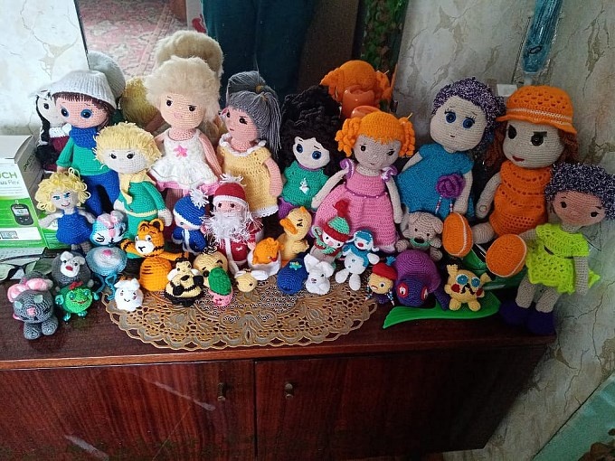 Множество вязаных кукол на тумбочке