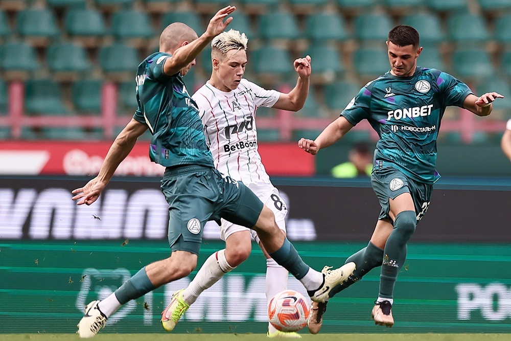    Игроки "Акрона" (слева и справа) пытаются отобрать мяч у полузащитника "Локомотива" Алексея Батракова. / Софья Сандурская/ТАСС