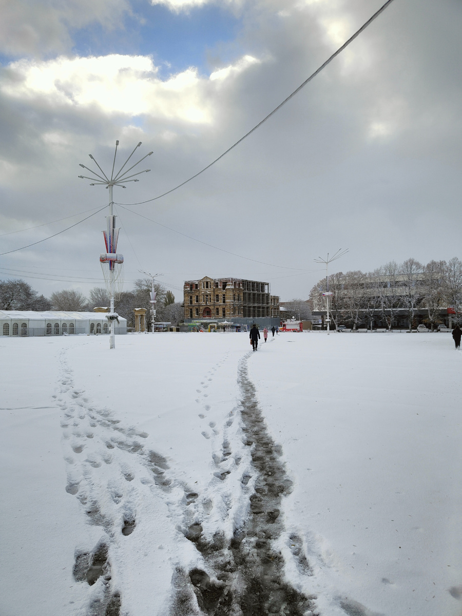 Театральная площадь, люди по протоптанным дорожкам спешат по своим делам 