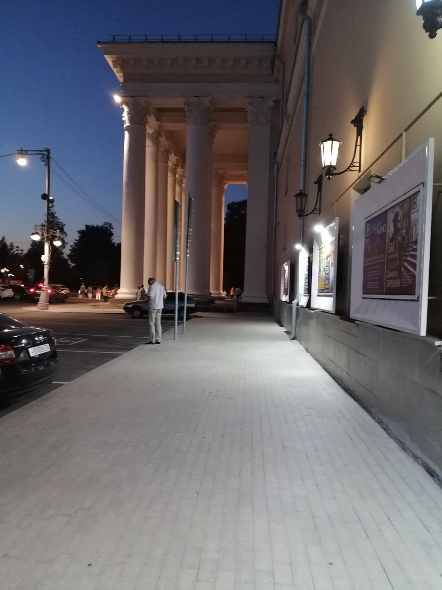 Афиши на стене здания (листайте по стрелке – всего 3 фотографии); впереди видны колонны Театра драмы, филармония к нему примыкает