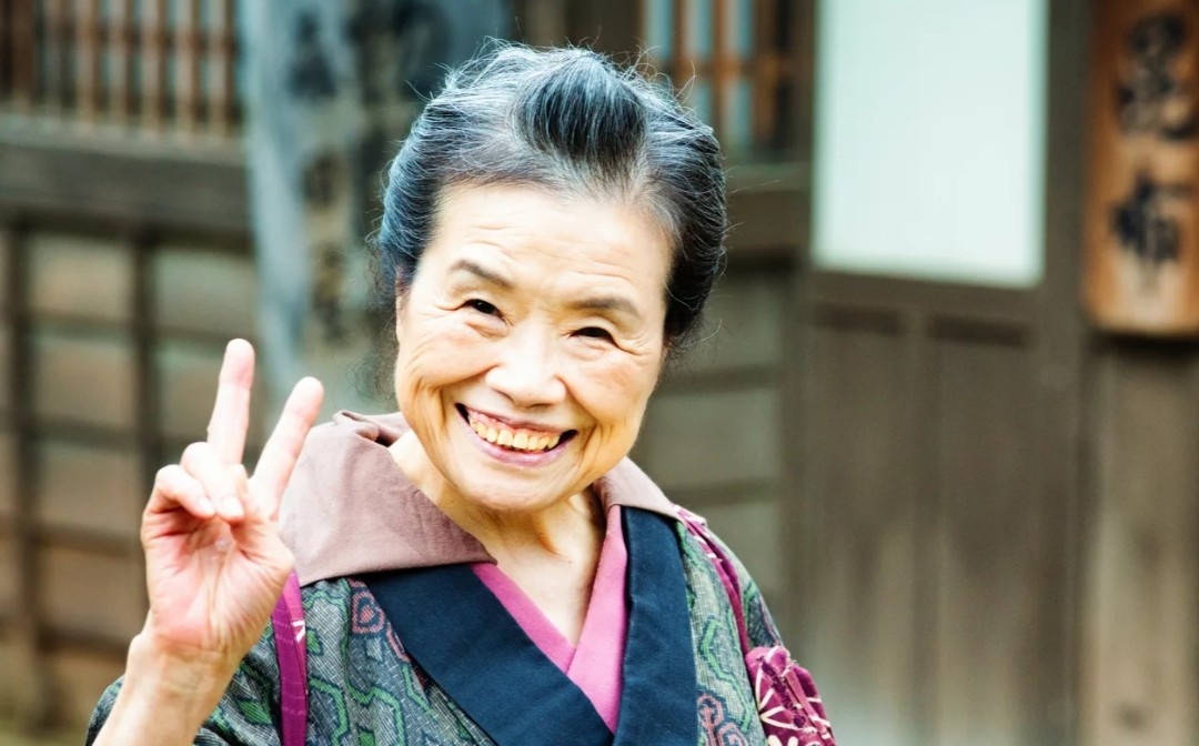 Япония славится своим выдающимся уровнем долголетия, что вызывает восхищение и интерес у людей по всему миру. На протяжении многих лет японцы занимают одни из лидирующих позиций в глобальных рейтингах средней продолжительности жизни. Давайте углубимся в детали, чтобы понять, что же стоит за этим феноменом, и какие аспекты японского образа жизни способствуют такому удивительному результату.

### Средняя продолжительность жизни в Японии

По состоянию на 2023 год, средняя продолжительность жизни в Японии составляет примерно 84 года, что значительно превышает мировые показатели. Женщины в этой стране, как правило, живут дольше мужчин, достигая в среднем 87 лет, тогда как мужчины, в свою очередь, имеют среднюю продолжительность жизни около 81 года. Этот разрыв в продолжительности жизни можно объяснить множеством факторов, включая образ жизни, питание и социальные условия, в которых живут японцы.

### Факторы, способствующие долголетию

1. **Сбалансированное питание**: Японская кухня считается одной из самых здоровых и разнообразных в мире. Основу рациона составляют свежие рыба и морепродукты, овощи, рис и соевые продукты, такие как тофу и натто. Употребление сезонных и местных продуктов позволяет японцам получать все необходимые витамины и минералы, поддерживая здоровье на высоком уровне.

2. **Умеренность в потреблении пищи**: Особая концепция "hara hachi bu" заключается в том, что японцы едят до тех пор, пока не почувствуют легкое насыщение, а не до полного. Этот подход помогает избежать переедания и способствует поддержанию здорового веса, что, в свою очередь, снижает риск возникновения хронических заболеваний.

3. **Физическая активность**: Японцы на протяжении всей своей жизни активно занимаются физической деятельностью. Прогулки, велосипедные поездки и занятия различными видами спорта становятся неотъемлемой частью их повседневной рутины. Такая активность способствует улучшению физического состояния и общего самочувствия.

4. **Социальные связи и поддержка**: Устойчивые социальные связи и активное участие в общественной жизни также играют важную роль в японской культуре долголетия. Участие в общественных мероприятиях, поддержка дружеских отношений и крепкие семейные узы помогают снизить уровень стресса и повышают общее качество жизни.

5. **Стрессоустойчивость и психическое здоровье**: Японская культура придает огромное значение психическому благополучию. Практики, такие как медитация, занятия традиционными искусствами и философия "икигай", помогают японцам сохранять эмоциональное равновесие и справляться со стрессом.

6. **Качественное медицинское обслуживание**: В Японии существует высокоразвитая система здравоохранения, которая обеспечивает доступ к качественной медицинской помощи. Регулярные медицинские осмотры и профилактические меры способствуют раннему выявлению заболеваний и их эффективному лечению, что значительно увеличивает шансы на долгую и здоровую жизнь.

### Продукты, способствующие долголетию

1. **Рыба и морепродукты**: Японцы потребляют огромное количество рыбы, что обеспечивает их организм необходимыми омега-3 жирными кислотами, полезными для сердечно-сосудистой системы и общего состояния здоровья.

2. **Овощи**: В рационе японцев присутствует множество овощей, особенно зеленых и корнеплодов. Они богаты клетчаткой и антиоксидантами, что способствует нормализации обмена веществ и укреплению иммунной системы.

3. **Соевые продукты**: Тофу и натто являются основными источниками белка и изофлавонов, которые помогают снижать риск сердечно-сосудистых заболеваний и поддерживают здоровье костей.

4. **Рис**: Японцы предпочитают рис как основной источник углеводов. Он легко усваивается и насыщает, не вызывая резких скачков сахара в крови, что является важным аспектом для поддержания стабильного уровня энергии.

5. **Зеленый чай**: Этот напиток, богатый антиоксидантами, обладает множеством полезных свойств, включая поддержку метаболизма, улучшение работы мозга и общий детокс организма.

### Заключение

Долголетие японцев — это результат сложного взаимодействия множества факторов, включая здоровый образ жизни, сбалансированное питание, активное участие в обществе и высококачественное медицинское обслуживание. Японская культура и традиции играют ключевую роль в формировании привычек, способствующих долгому и здоровому существованию. Изучение этих аспектов может предоставить ценные уроки для других стран, стремящихся улучшить здоровье и качество жизни своих граждан, а также вдохновить на внедрение более здоровых практик в повседневную жизнь.