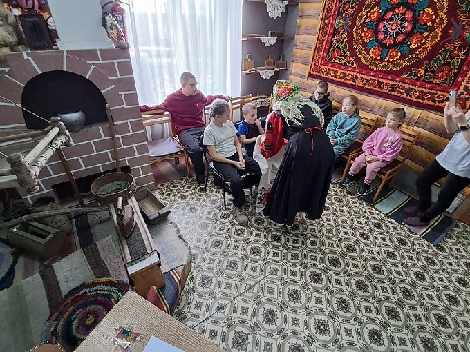 Женщина в народном костюме угощает детей хлебом с солью