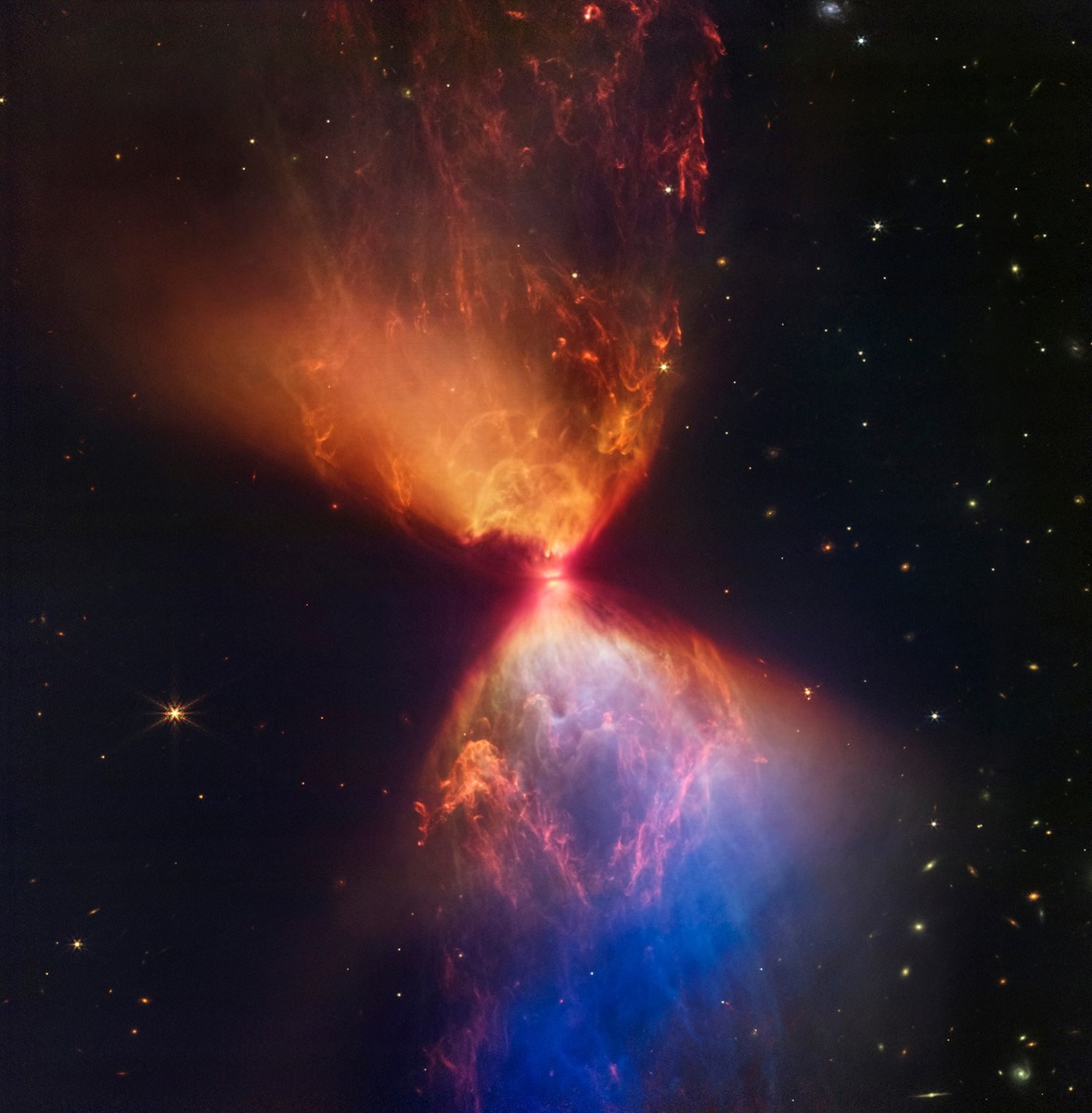 While Webb cannot see the very first stars, the telescope has captured stunning views of star formation closer to Earth. A star in the process of sparking to life blows material out into an hourglass shape.