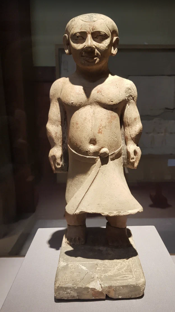 5-я династия, около 2465-2323 гг. до н.э., Саккара, известняк, пигмент, CG 144 Хнумхотеп был жрецом и надзирателем за царским гардеробом, а ка - слугой. Его имя и титулы высечены на основании статуи. 