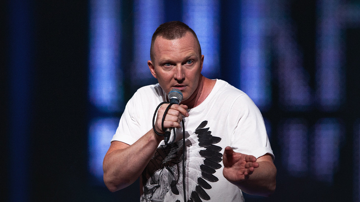 Стендап-комик шутит над людьми, которые тренируются в фитнес-клубе с видом на парк.