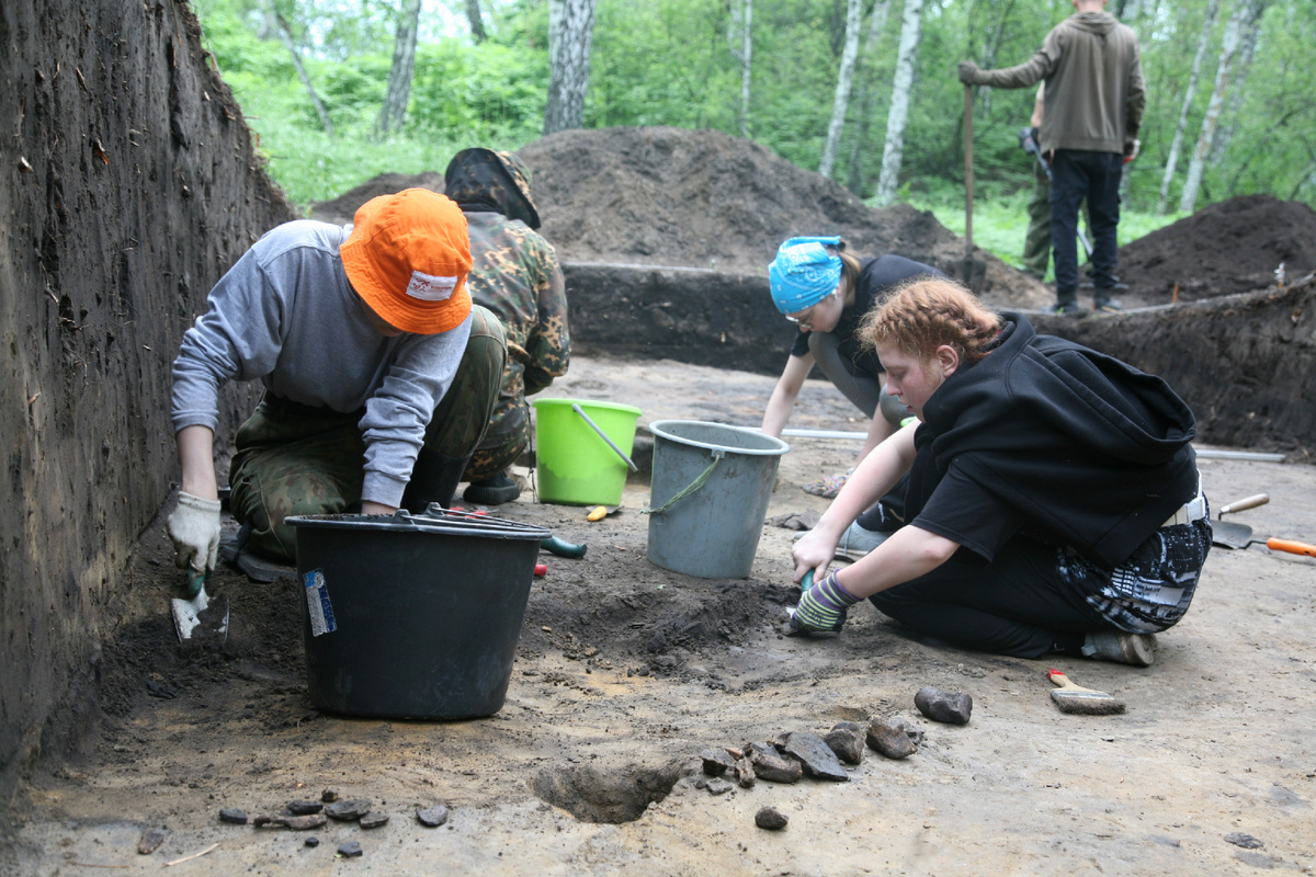 Студенты за разбором скопления костей и керамики. Автор фото: М. М. Проконова